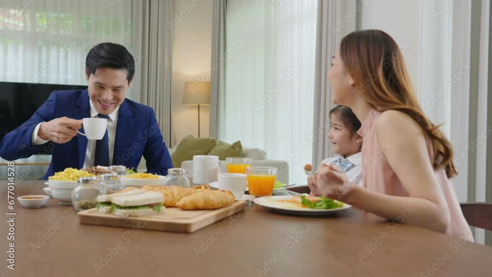 Asian family father, mother with children daughter eating healthy breakfast food on dining table kitchen in mornings together at home before father left for work, happy couple adult family concept Asian family father, mother with children daughter eating healthy breakfast food on dining table kitchen in mornings together at home before father left for work, happy couple adult family concept