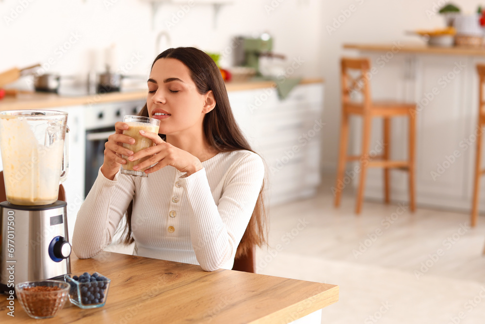 Young woman with glass of healthy smoothie in kitchen Young woman with glass of healthy smoothie in kitchen