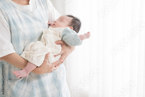 赤ちゃんの出産や検診イメージ( 顔無しの助産師、ママ、保育士、保健師、に抱っこされ寝るベビー）クローズアップ 右にコピースペースあり photo