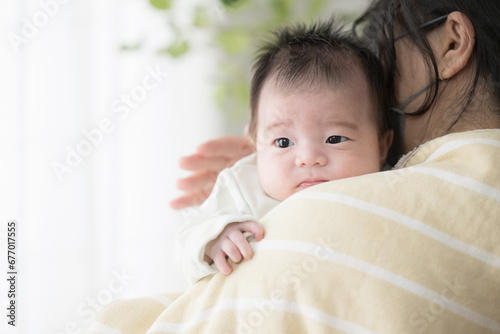 ママに抱っこされ背中をトントンしてゲップを促されるベビー服姿の赤ちゃん photo