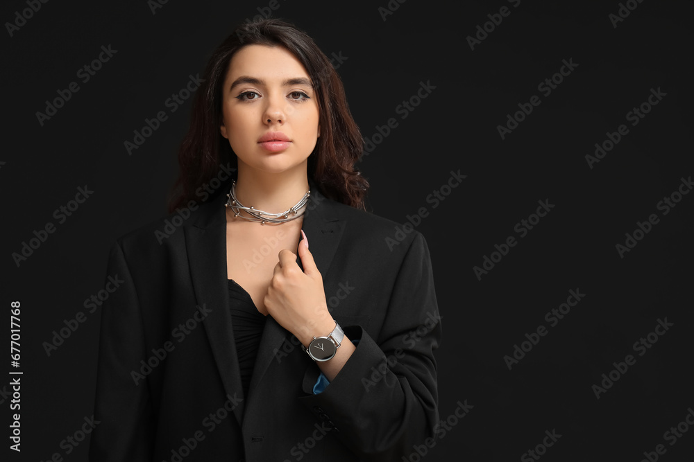 Beautiful young woman with wristwatch on black background