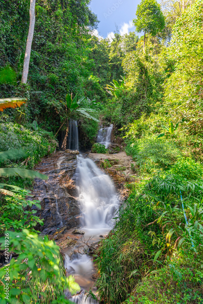 Obraz premium beautiful cascading waterfall over rocks long exposure in Chiangmai Chiang mai mountains northern thailand amongst lush green tropical rainforest