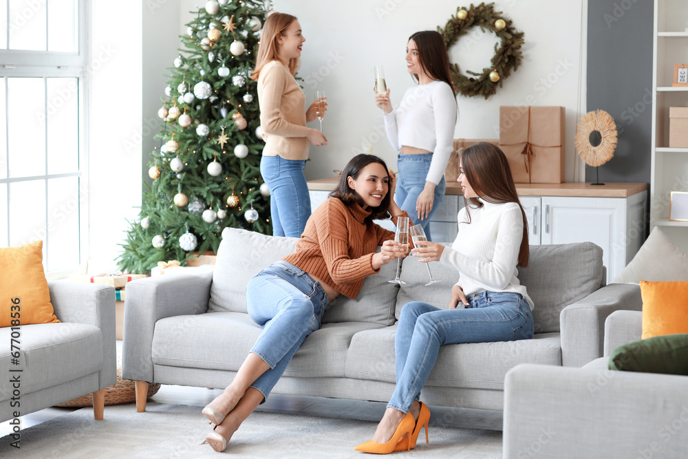 Beautiful young women with glasses of champagne waiting Christmas at home