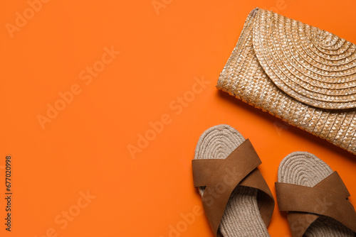 Stylish brown sandals and wicker bag on orange background photo
