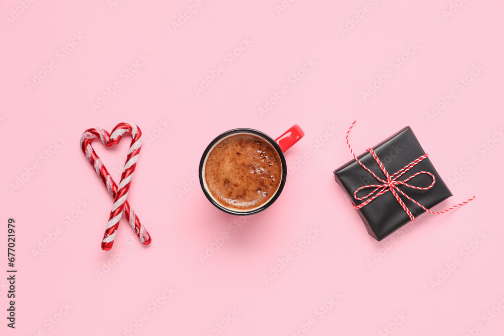Mug of coffee with gift box and candy canes on pink background Mug of coffee with gift box and candy canes on pink background