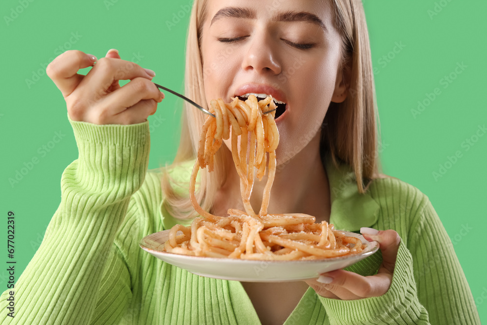 Young woman eating tasty pasta on green background, closeup Young woman eating tasty pasta on green background, closeup