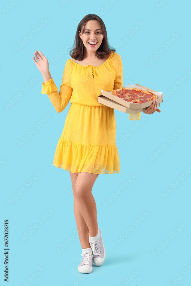 Young woman with tasty pepperoni pizza on blue background Young woman with tasty pepperoni pizza on blue background