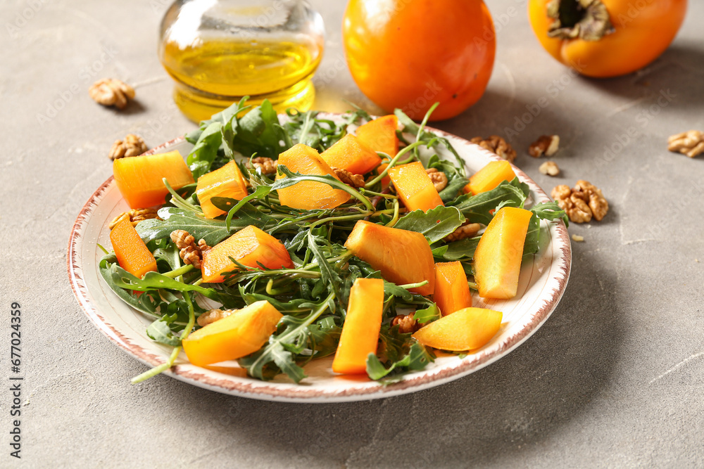 Plate of delicious salad with persimmon and walnut on grey background Plate of delicious salad with persimmon and walnut on grey background