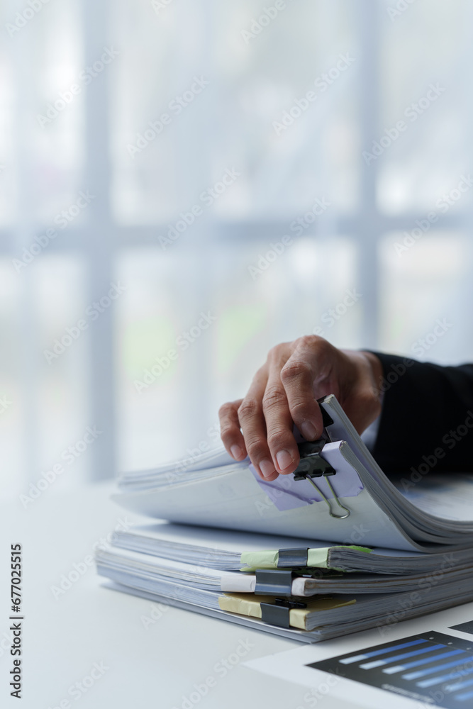 Asian businesswoman searches through piles of financial documents to make calculations Marketing analysis Tax administration Statistical accounting report on the desk in the office office. - obrazy, fototapety, plakaty 