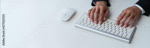 Cropped view of businessman typing on keyboard Hand typing on wireless computer keyboard and mouse in office, writing, typing email or communicating online. photo