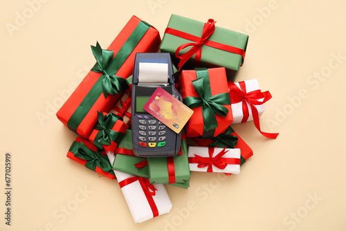 Payment terminal with credit card and Christmas gift boxes on yellow background