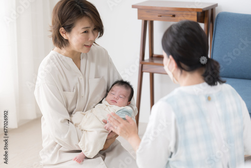 新生児や乳幼児の1ヶ月訪問をうける母親 心配で相談する赤ちゃん訪問の様子