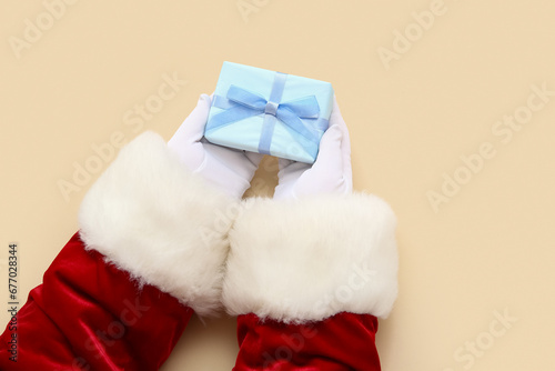 Santa Claus with blue gift box on beige background