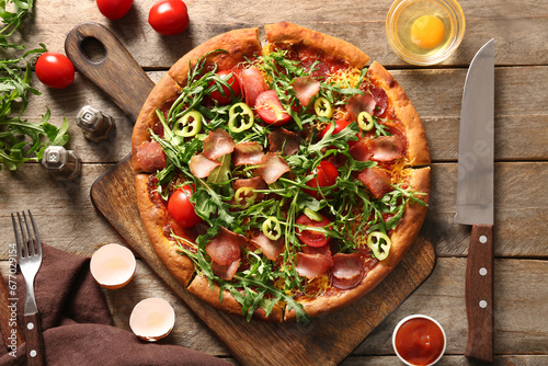 Board of delicious pizza with tomatoes and arugula on wooden background