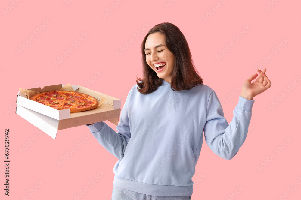 Happy young woman holding cardboard box with tasty pizza on pink background Happy young woman holding cardboard box with tasty pizza on pink background