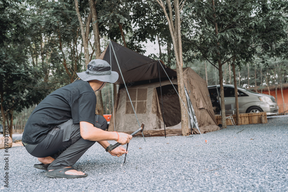 Outdoor tourists are setting up camping tents on rocky ground under trees on vacation. Outdoor tourists are setting up camping tents on rocky ground under trees on vacation.