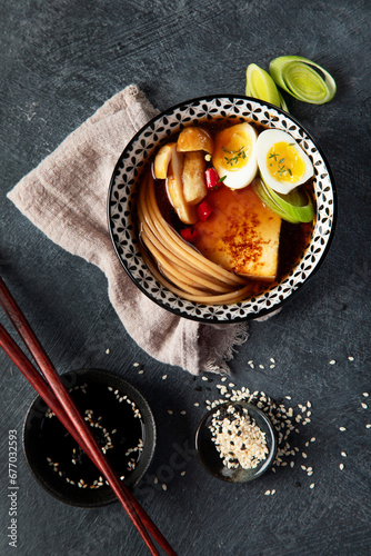 Asian soup with egg, tofu, mushrooms and onion on black background. Traditional food concept.