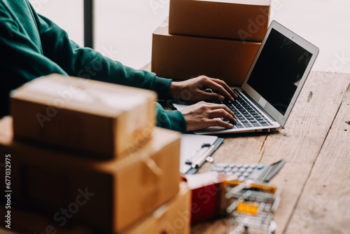 Startup small business entrepreneur or freelance Asian woman using a laptop with box, Young success Asian woman with her hand lift up, online marketing packaging box and delivery, SME concept. © ARMMY PICCA