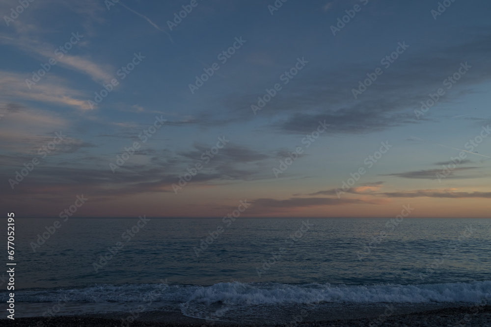 Sunset on the French Riviera pebble beach in Nice with straight horizon line