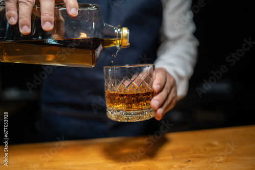 Bartender pours whiskey to customer in tavern