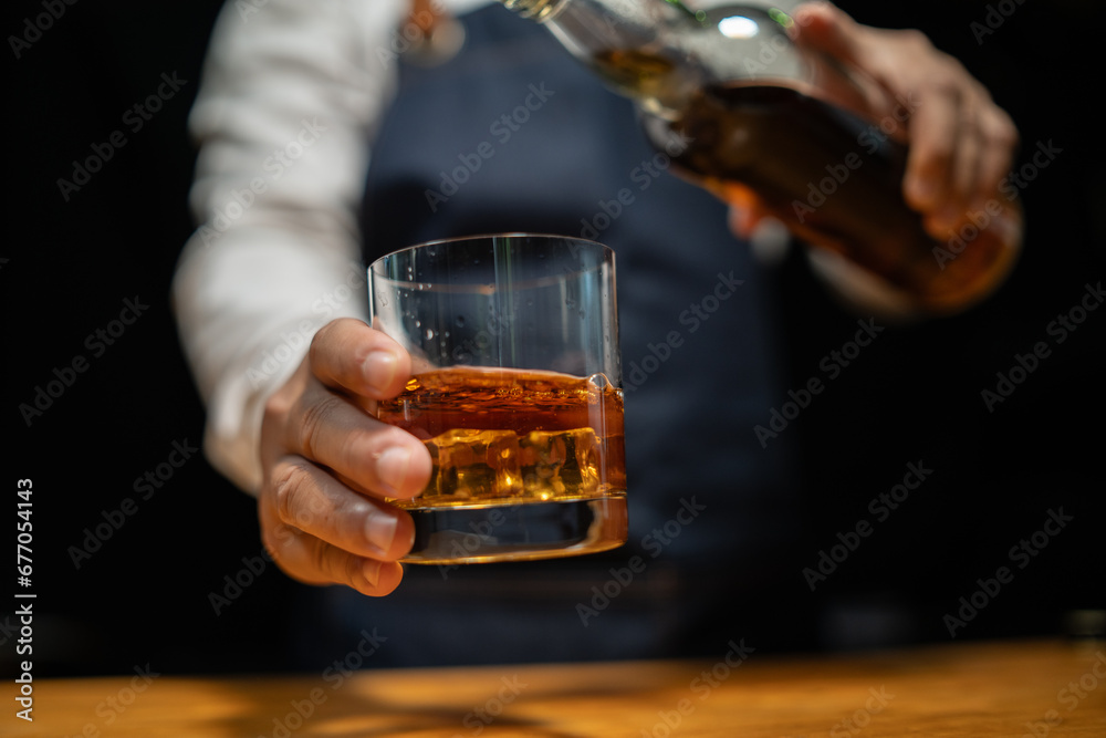 Bartender pours whiskey to customer in tavern Bartender pours whiskey to customer in tavern