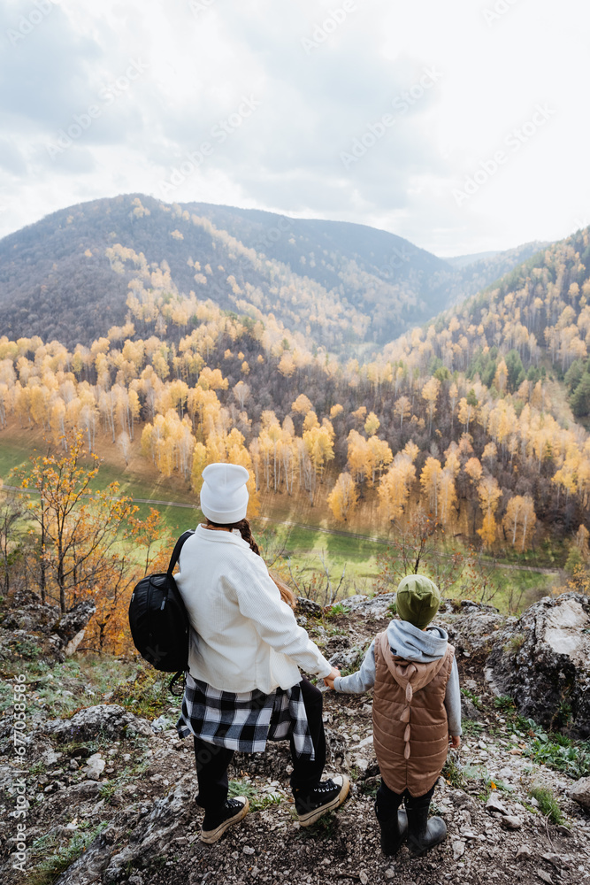 Family vacation in nature, mother and son walking in the mountains, hiking in the autumn forest, school holidays, trekking in the mountains.