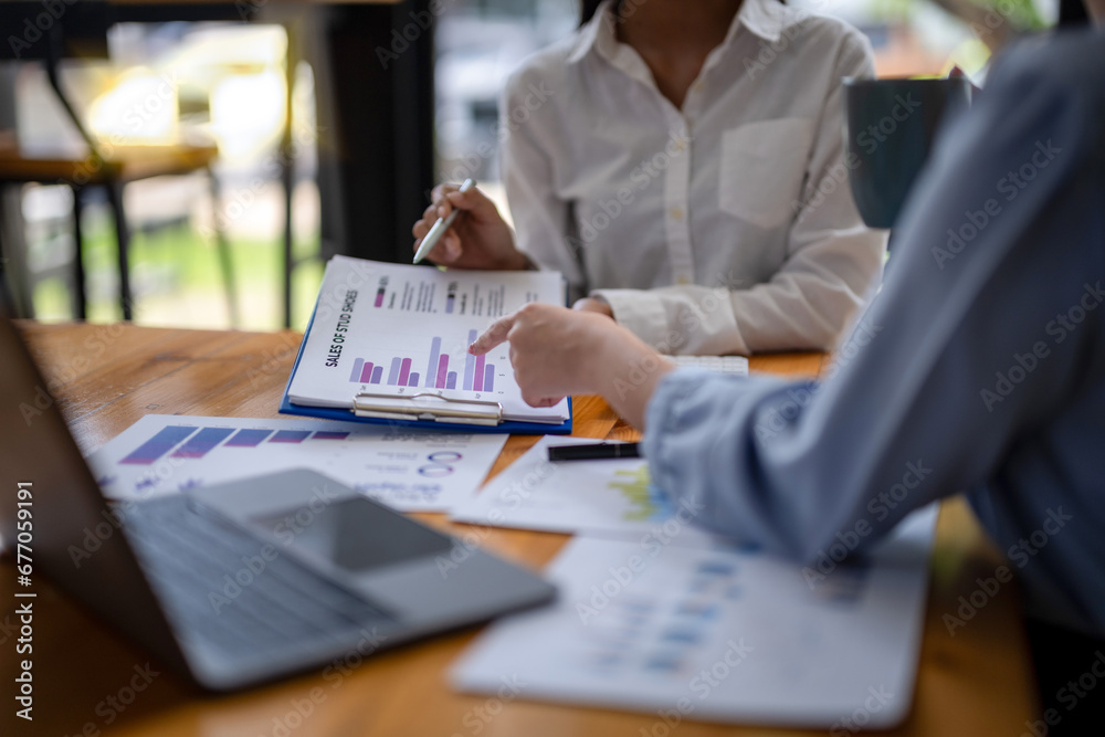 Focusing on data, two businesswomen talk at the table and brainstorm business ideas. Providing advice and marketing planning Focusing on data, two businesswomen talk at the table and brainstorm business ideas. Providing advice and marketing planning