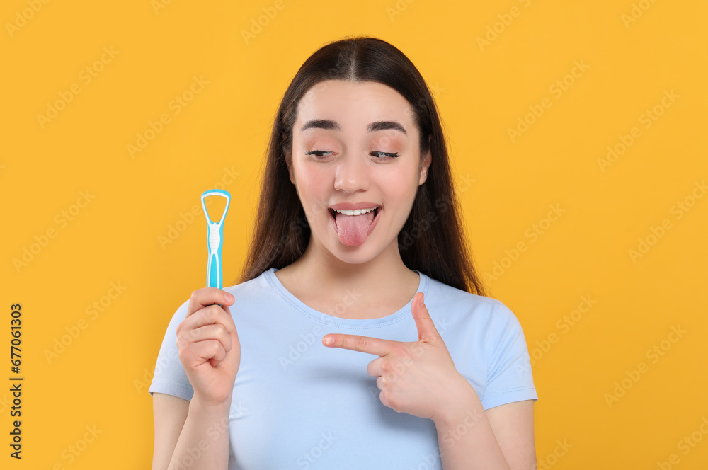 Happy woman showing tongue cleaner on yellow background Happy woman showing tongue cleaner on yellow background