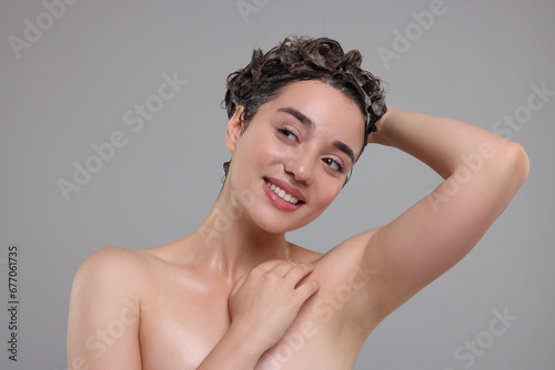 Portrait of beautiful happy woman washing hair on grey background