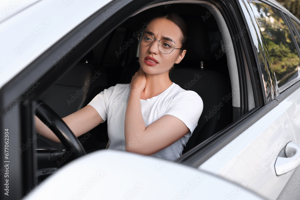 Young woman suffering from neck pain in her car Young woman suffering from neck pain in her car