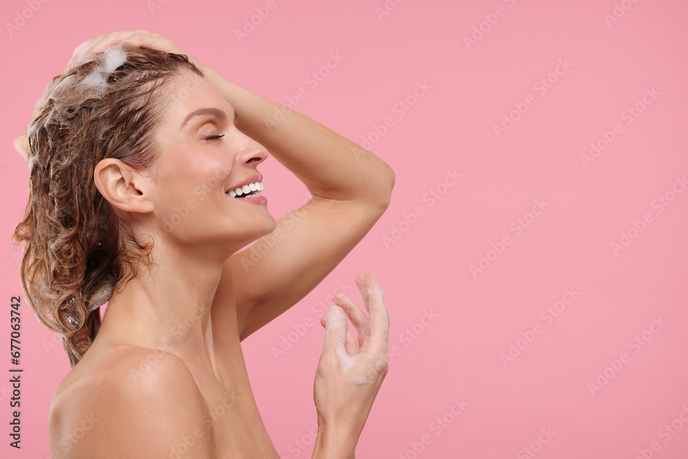 Beautiful happy woman washing hair on pink background. Space for text Beautiful happy woman washing hair on pink background. Space for text