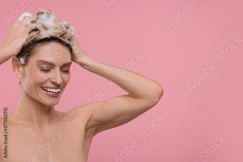 Beautiful happy woman washing hair on pink background. Space for text