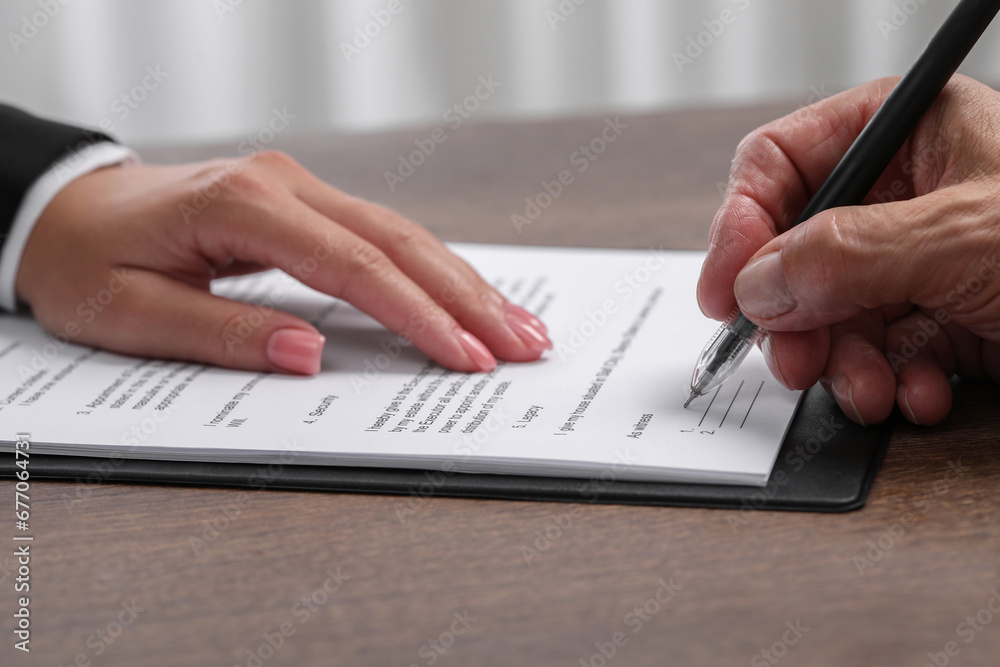 Manager showing client where he must to mark signature at wooden table indoors, closeup Manager showing client where he must to mark signature at wooden table indoors, closeup