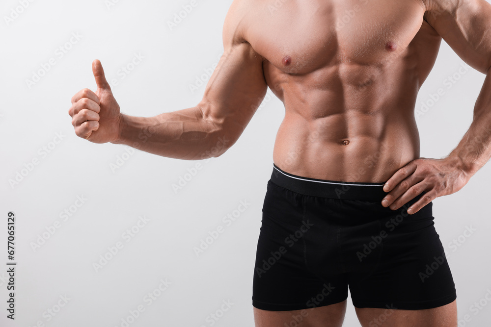 Young man is stylish black underwear showing thumb up on light grey background, closeup Young man is stylish black underwear showing thumb up on light grey background, closeup