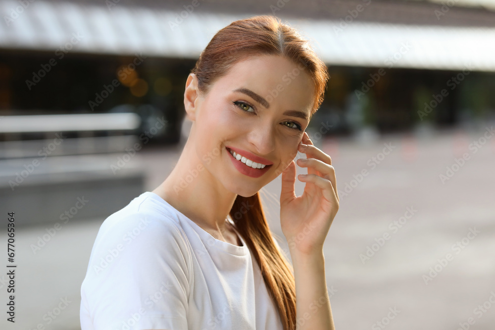 Fototapeta premium Portrait of happy young woman in casual clothes outdoors. Attractive lady smiling and looking into camera