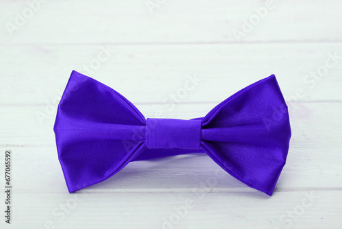Stylish neon blue bow tie on white wooden table, closeup