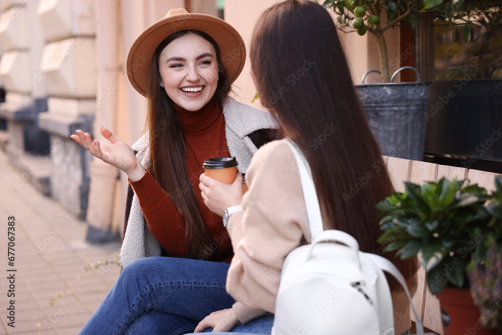Obraz premium Happy friends with paper cups of coffee talking outdoors