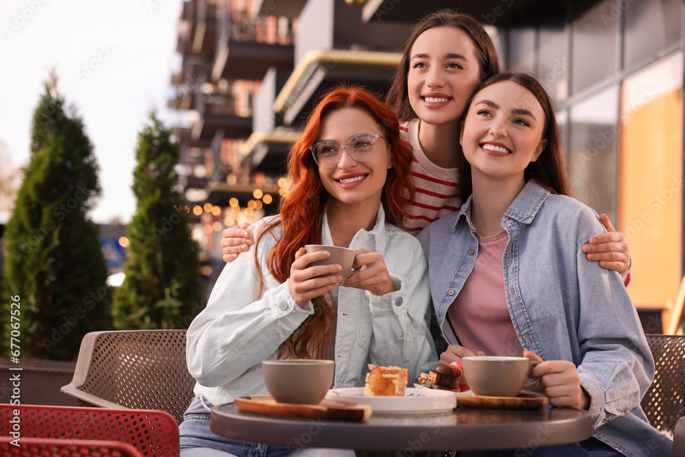 Happy friends drinking coffee in outdoor cafe. Space for text