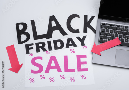 Napisy ułożone z literek Black Friday i sale obok laptopa na jasnym tle