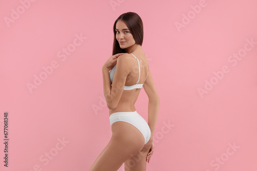 Young woman in stylish white bikini on pink background