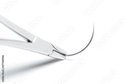 Macro photo of artery forceps holding half circle cutting needle on white background. 