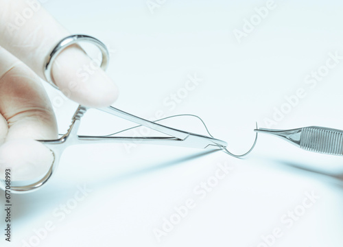 Surgeon holding half circle cutting needle and suture with forceps on white background. Suture thread, medical concept. photo