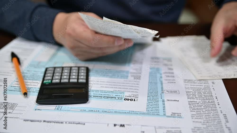 A man organizing individual income tax return form 1040 and receipts. Blurred background. Tax time.Tax concept. Close-up.