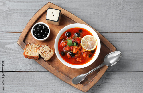 Meat solyanka soup with sausages, olives and vegetables in bowl served on grey wooden table, top view