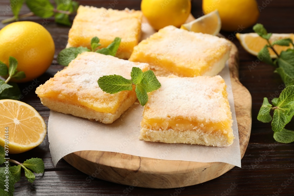 Tasty lemon bars with powdered sugar and mint on wooden table, closeup Tasty lemon bars with powdered sugar and mint on wooden table, closeup