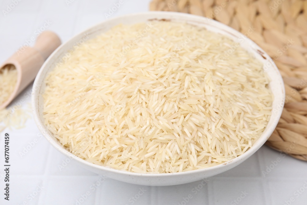 Raw rice in bowl on white tiled table, closeup Raw rice in bowl on white tiled table, closeup