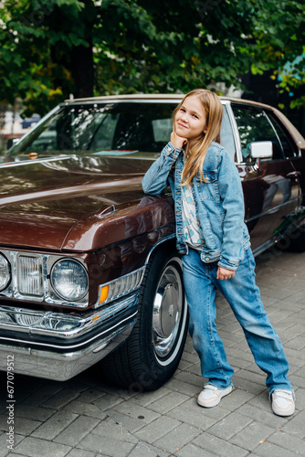Teenage girl in denim clothes by vintage brown car.