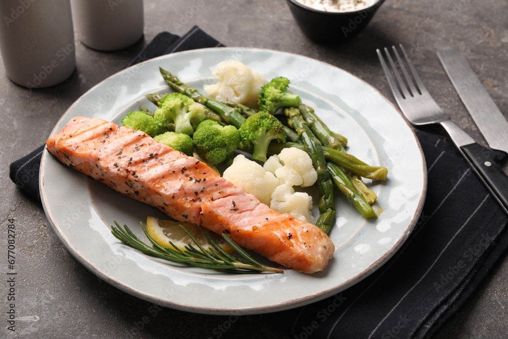 Healthy meal. Piece of grilled salmon, vegetables, asparagus and rosemary served on grey textured table, closeup