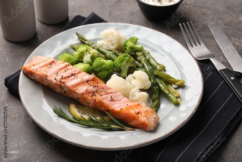 Healthy meal. Piece of grilled salmon, vegetables, asparagus and rosemary served on grey textured table, closeup