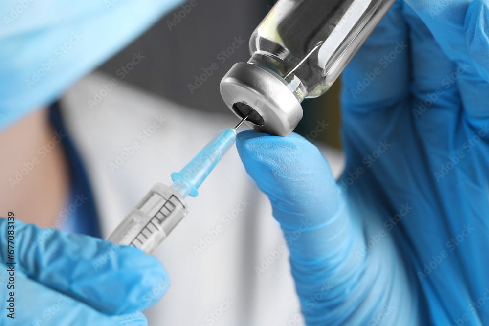 Doctor filling syringe with medication from glass vial, closeup Doctor filling syringe with medication from glass vial, closeup
